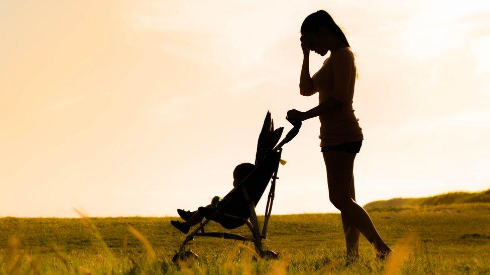 silhouette of woman with baby in pushchair with her head in her hands