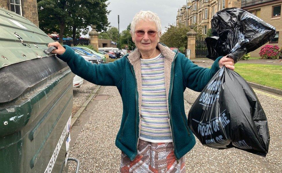 Mary Nisbet putting rubbish in her bin