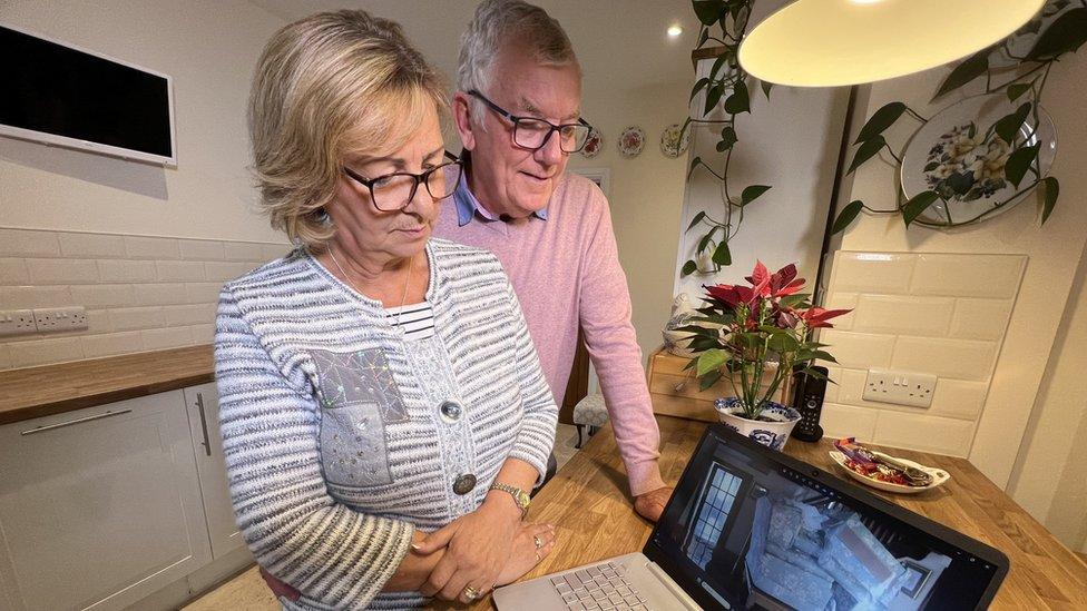 Maria and Phil looking at the laptop of pictures from the flood