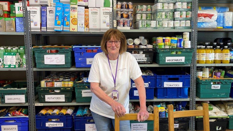 Broke Not Broken stock controller Susan in front of a large shelf full of different types of food