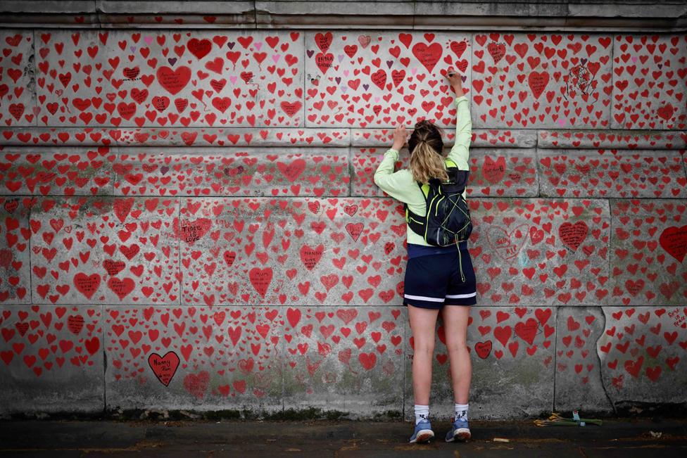 A woman draws on the National Covid Memorial Wall