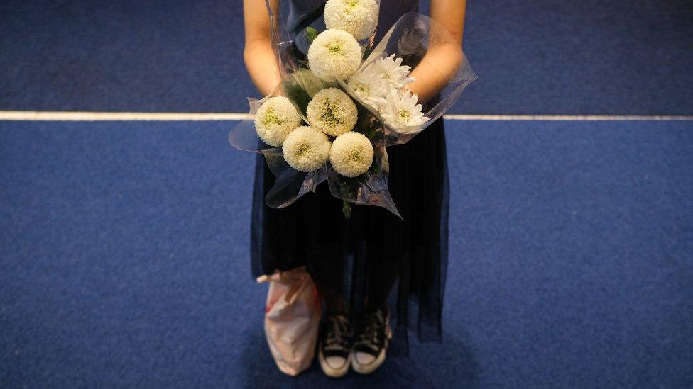 A woman held flowers at the scene to mourn the dead who was suspected of stabbing the police.