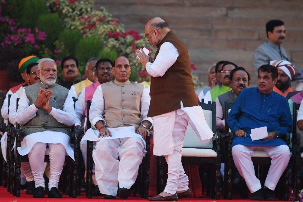 Amit Shaha (C) takes gestures towards newly sworn-in Indian Prime Minister Narendra Modi (L) before taking the oath of office as cabinet minister at the President house in New Delhi on May 30, 2019.