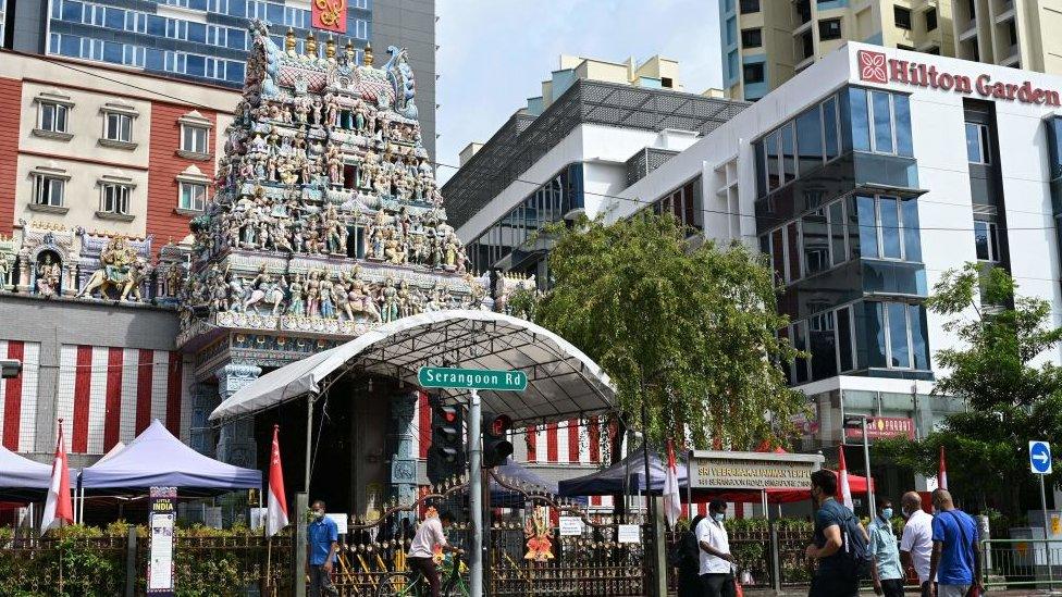 Pedestrians cross the road in front of the Sri Veeramakaliamman temple in the district of Little India in Singapore on September 15,