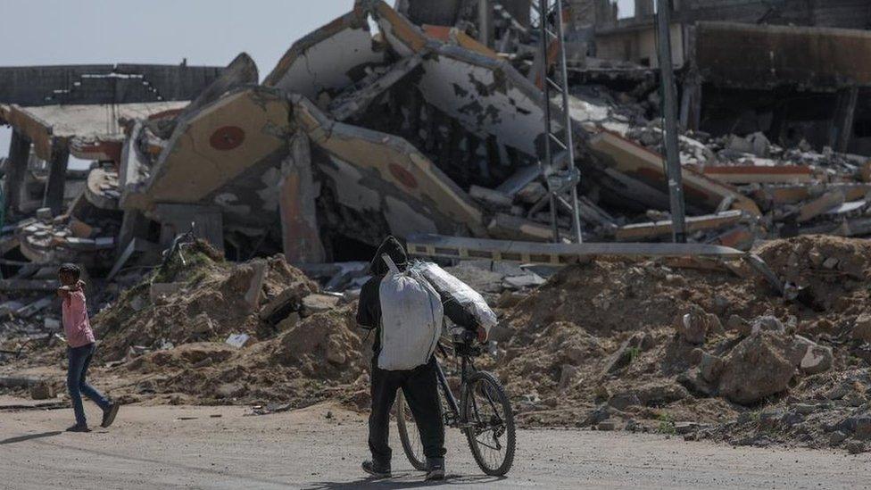 A displaced Palestinian man pushes a bike along Salah al-Din road in southern Gaza after fleeing Rafah (9 May 2024)