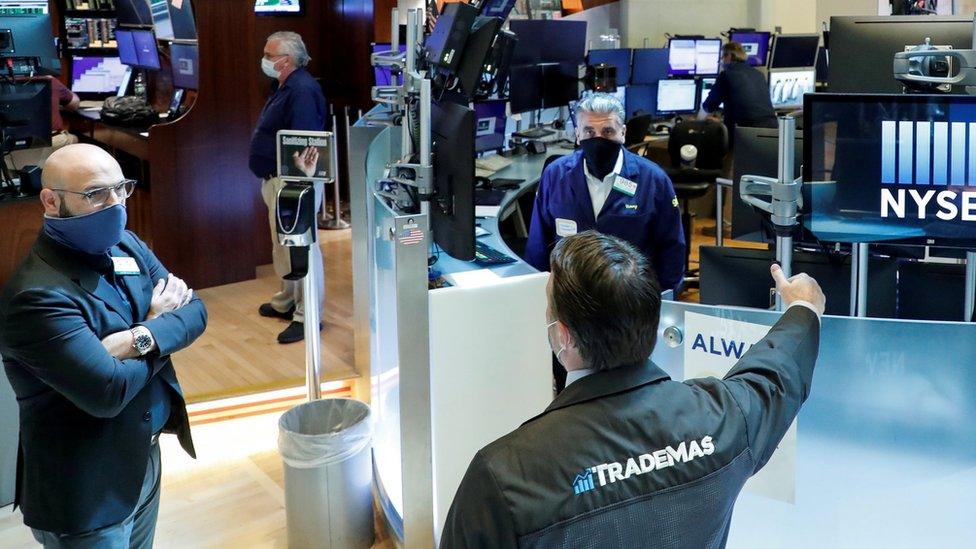 Traders wearing masks work, on the first day of in person trading since the closure during the outbreak of the coronavirus disease (COVID-19) on the floor at the NYSE in New York