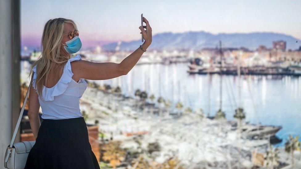 Woman in mask takes selfie on holiday