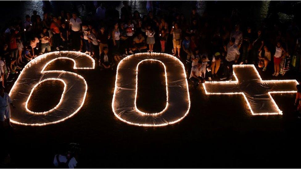 People light candles and form the 60+ sign on March 30, 2019 in Cali, Colombia, during the a Earth Hour organised by the green group WWF.