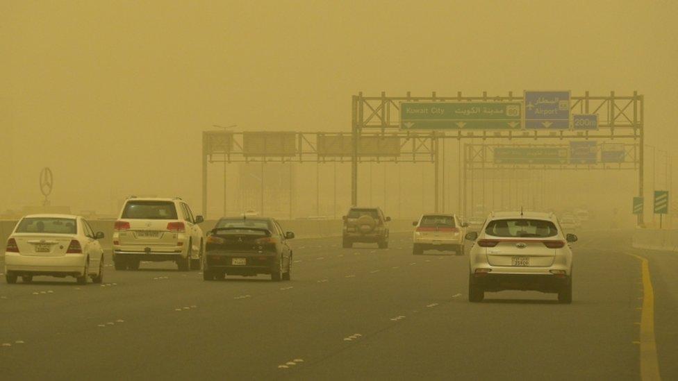 Vehicles transit at a road shrouded in heavy dust in Kuwait City, Kuwait, 13 June 2021