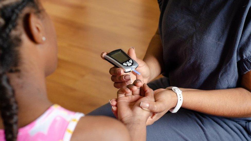 A young girl having her blood glucose levels monitored