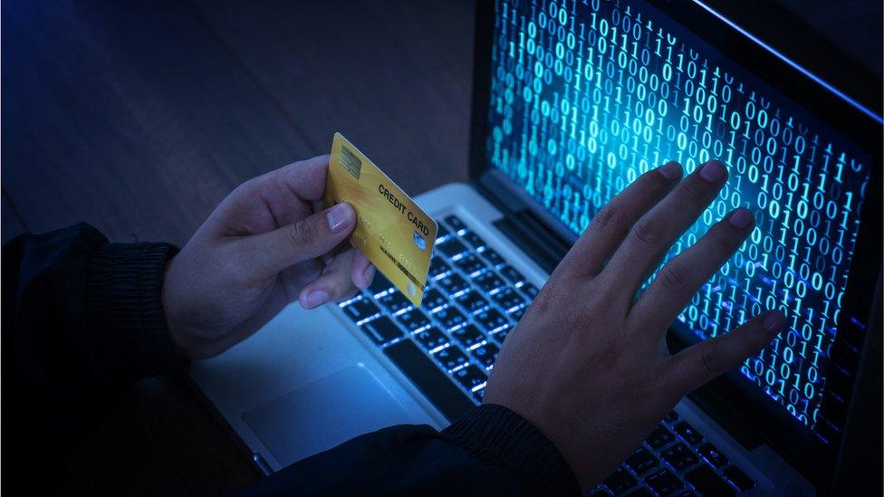 man holding credit card in darkened room