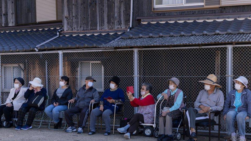 An elderly woman uses her smartphone to take pictures while she looks at ‘Sisimai’, a traditional Japanese lion dance performed by Ise Daikagura performing troupe on October 13, 2022 in Inujima, Japan.