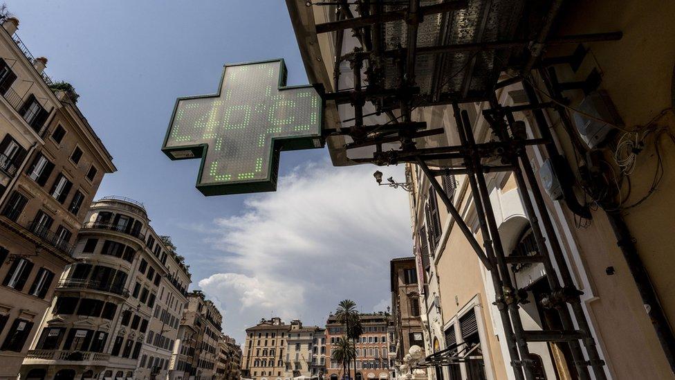 Photo of an Italian street with a large pharmacy sign showing an air temperature of 40C