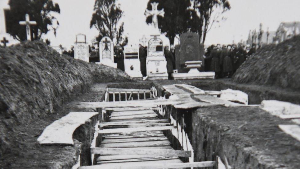 A reproduction of a photograph showing coffins after the massacre of Ascq in 1944 during WWII