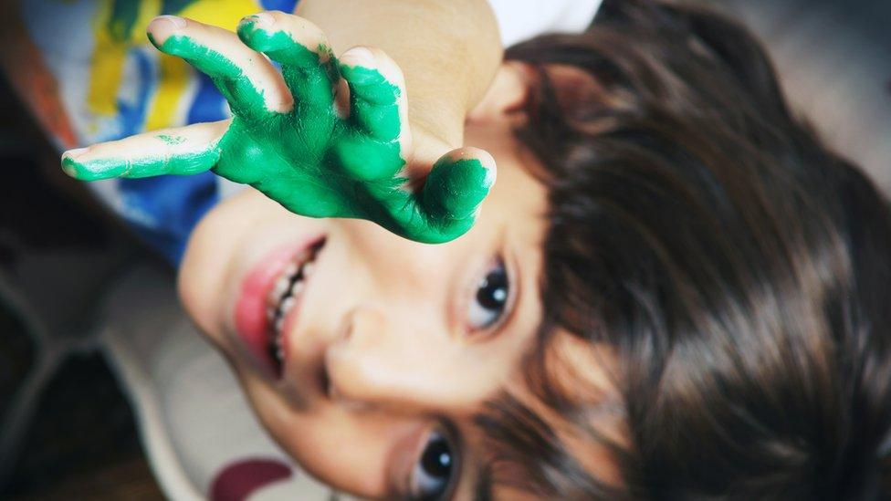 Child with green paint on their hand