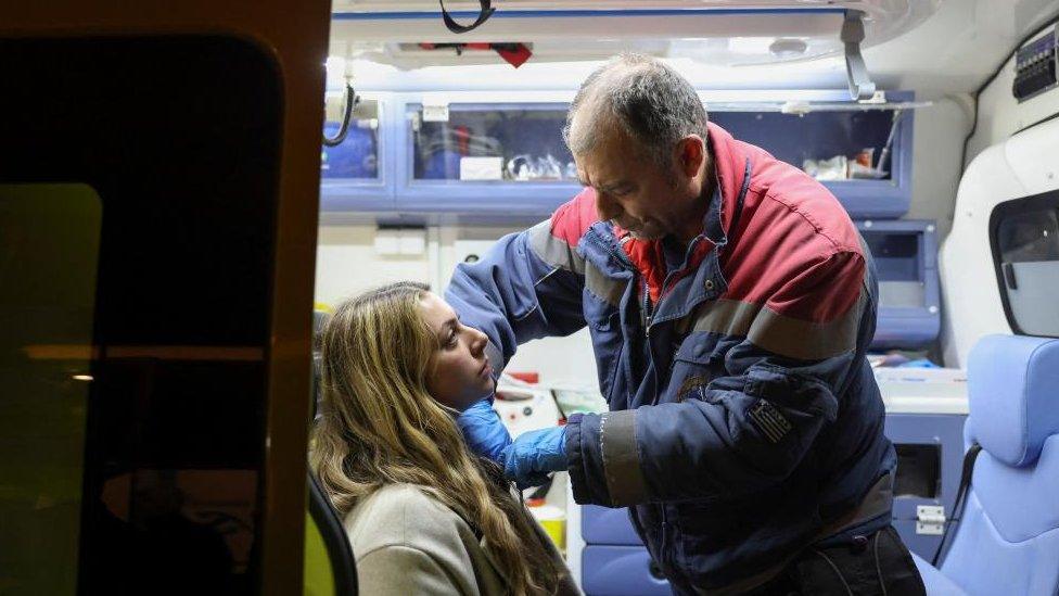 A male paramedic attends to an injured woman in an ambulance