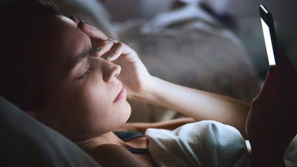 Woman in bed with smartphone