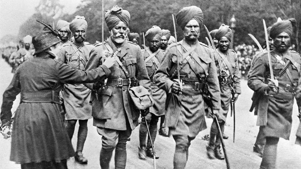 During a march past of Indian troops, a woman pins flowers on to the tunic of one of the soldiers.