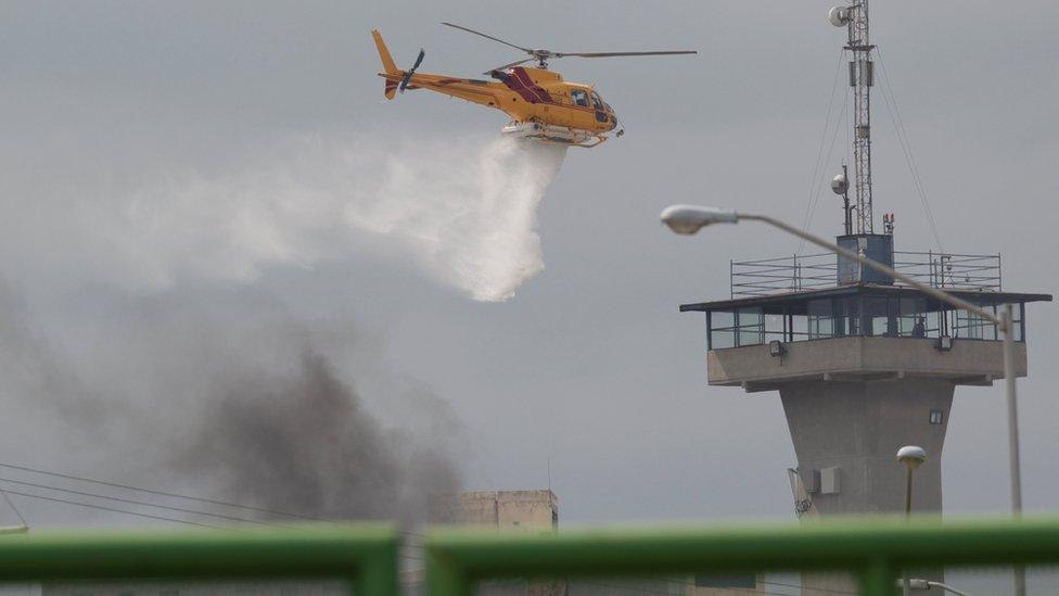 A helicopter drops water to extinguish a fire after a riot broke out at the Cadereyta state prison, in Cadereyta Jimenez