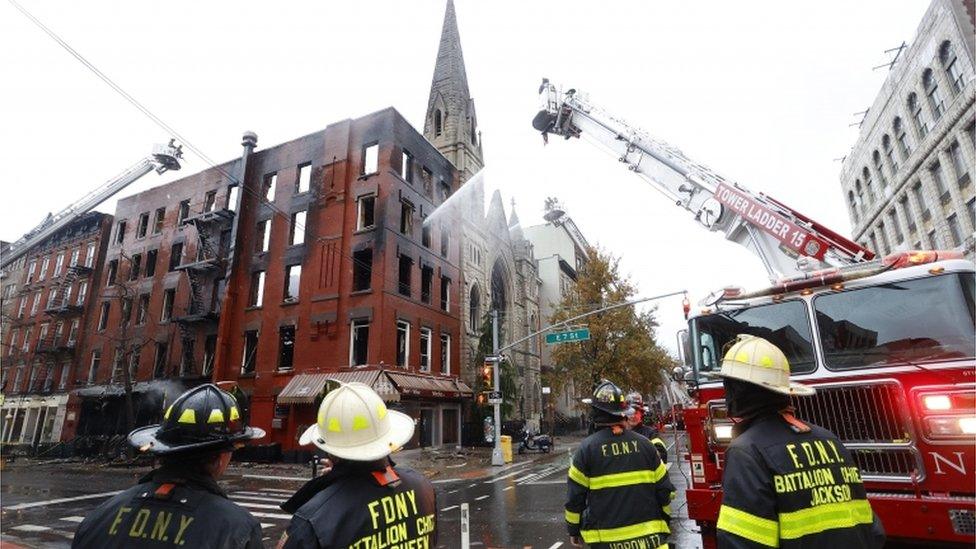 Firefighters stand in front of Middle Collegiate Church after a blaze gutted the building