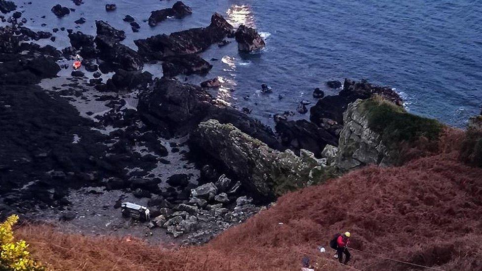 Car on its side at the bottom of the cliff