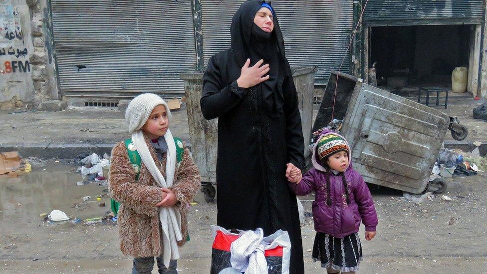 A Syrian woman arrives in Aleppo's Fardos with her children in Aleppo's Fardos neighbourhood after regime troops retook the area from rebel fighters, 13 December 2016