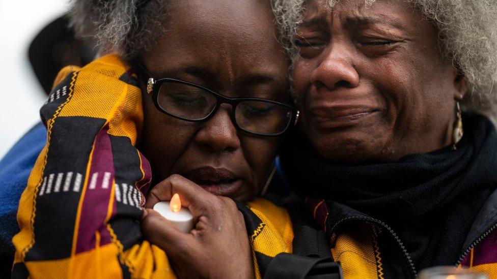 Two women crying at a vigil