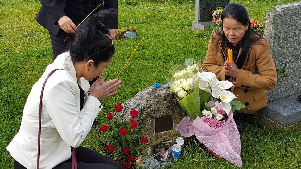 Two women kneeling at a gravestone