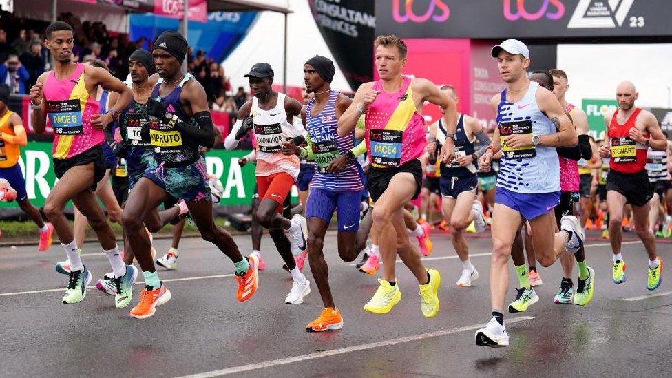 Runners setting off from start line where there are many signs