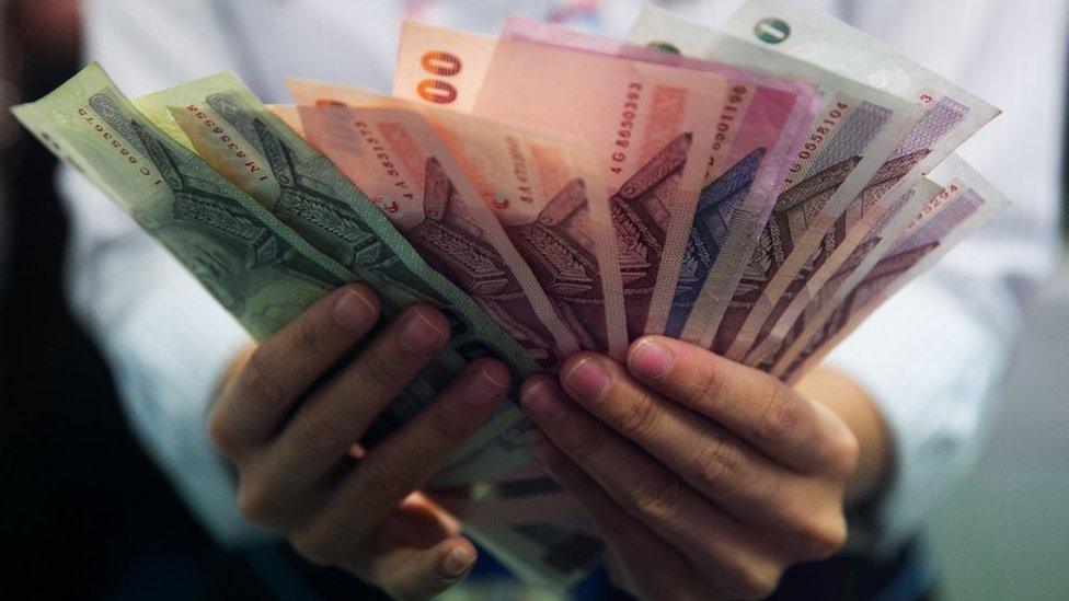 A money exchange bank teller counts Thai bhat in Bangkok, Thailand.