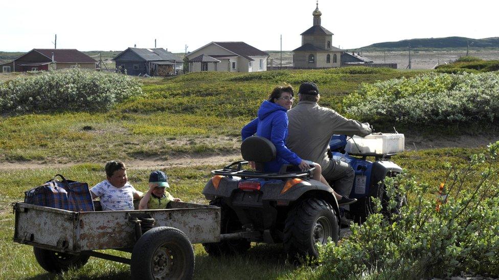 Children ride in a trailer in the village of Chavanga, in Russia's Arctic Murmansk region.