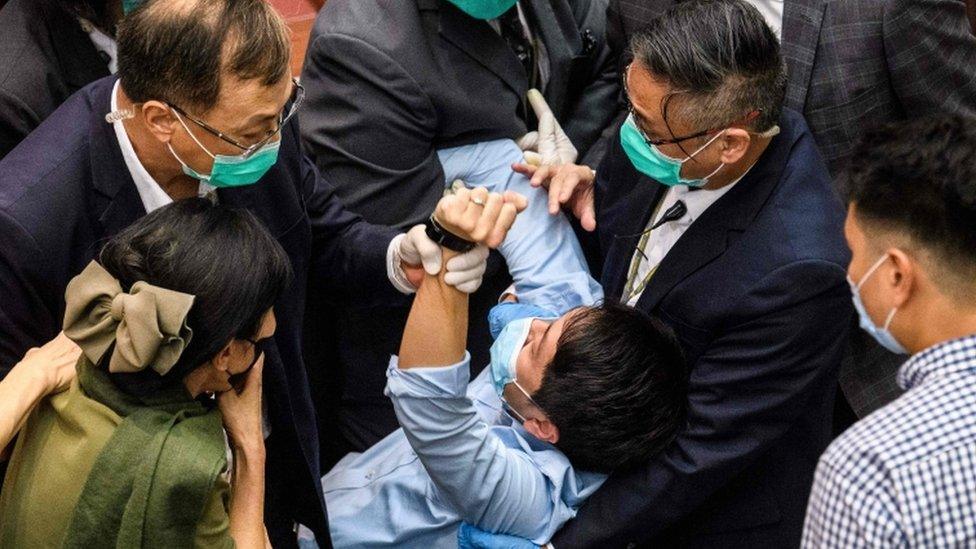 A pro-democrat lawmaker is restrained by security guards at the Legislative Council in Hong Kong