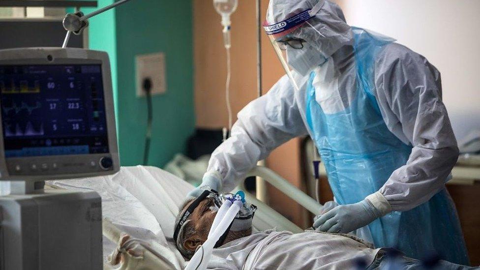 A medical staff member wearing Personal Protective Equipment (PPE) suit looks after a Covid-19 patient at the Intensive Care Unit of the Sharda Hospital, in Greater Noida near Delhi