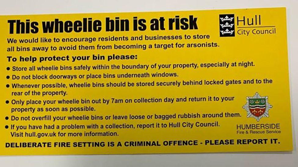 The yellow tag attached to bins saying "This wheelie bin is at risk" with advice on how to avoid arson attacks with the Hull City Council and Humberside Fire and Rescue Service