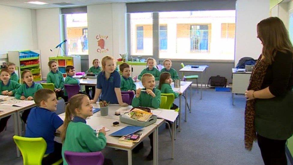 Children in class smile at their supply teacher