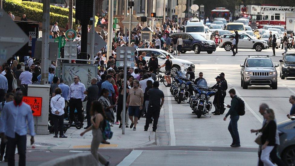 People wait outside after evacuating office buildings in Miami, Florida after an earthquake struck in the Caribbean