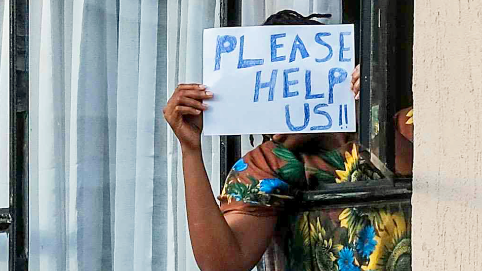 Someone in quarantine in Kenya holding up a "Please help us" sign - April 2020