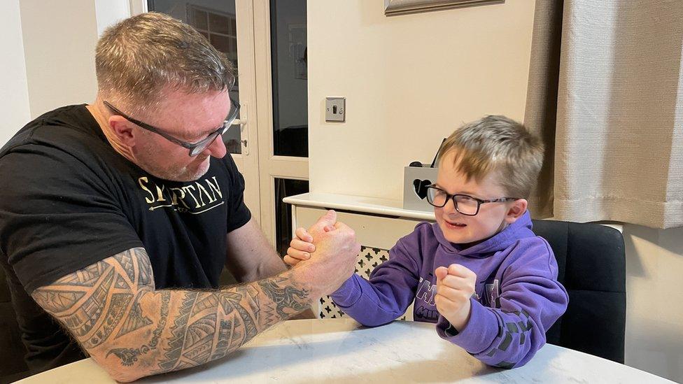 Mark Waldon arm wrestles his 7 year old grandson Daniel on a dining table