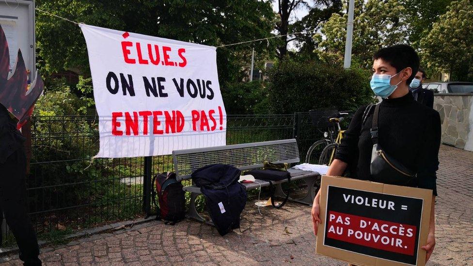 A woman holds a sign that reads 'Rapist = no access to power'