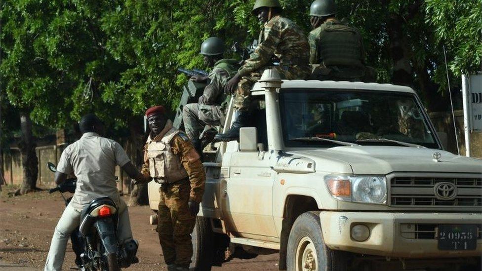 A man riding a motorcycle speaks with a member of Burkina Faso army troops standing guard outside Sangoule Lamizana military camp in Ouagadougou on September 22, 2015.