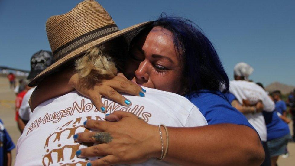 Mexican families living in US and Mexico embrace at the border in El Paso, Texas