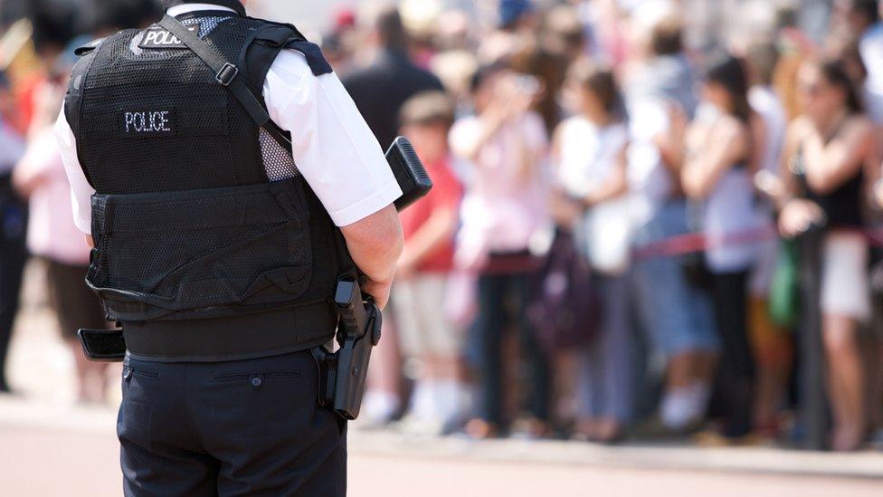 An armed policeman by a crowd of people