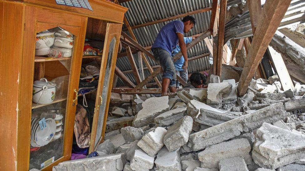 A villager walks through the ruins of a collapsed house during a search for the equipment of Malaysian tourists who died during the earthquake at the Sembalun Selong village in Lombok Timur, Indonesia, 29 July 2018