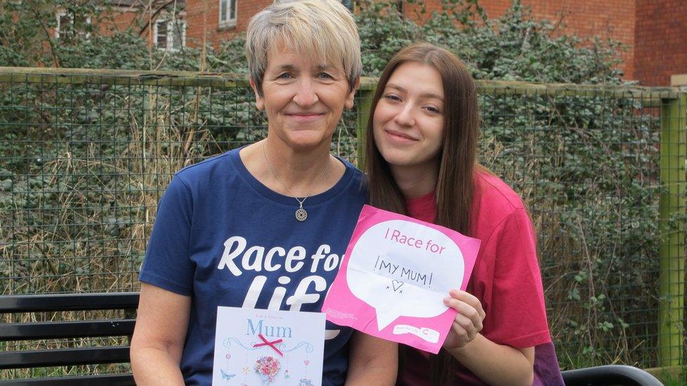 Jacqui and Jaigh in their Race For Life t shirts, holding a sign that says "I race for my mum"