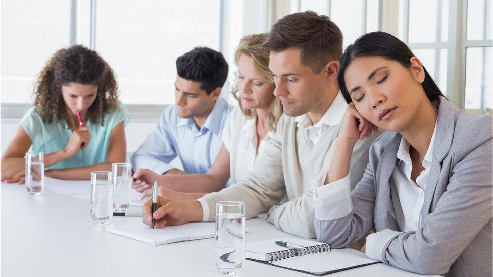 People in meeting, one woman falling asleep