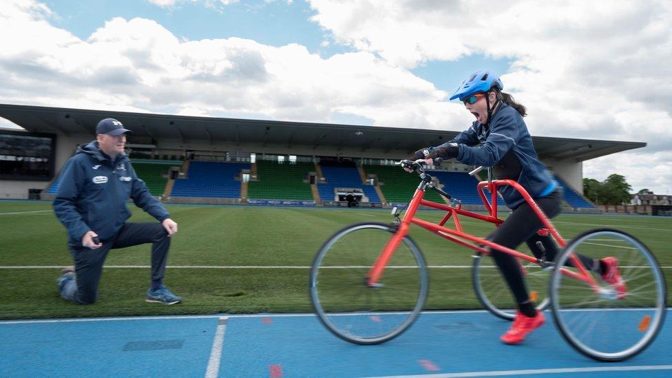 Julie McElroy on a red frame runner on a track with coach Gordon Innes