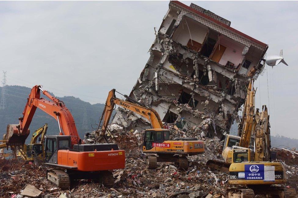 Diggers alongside a ruined building at the site