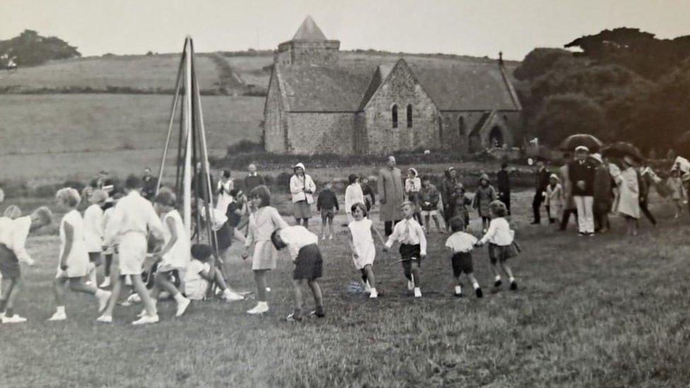 Children dressed in white dancing around the maypole