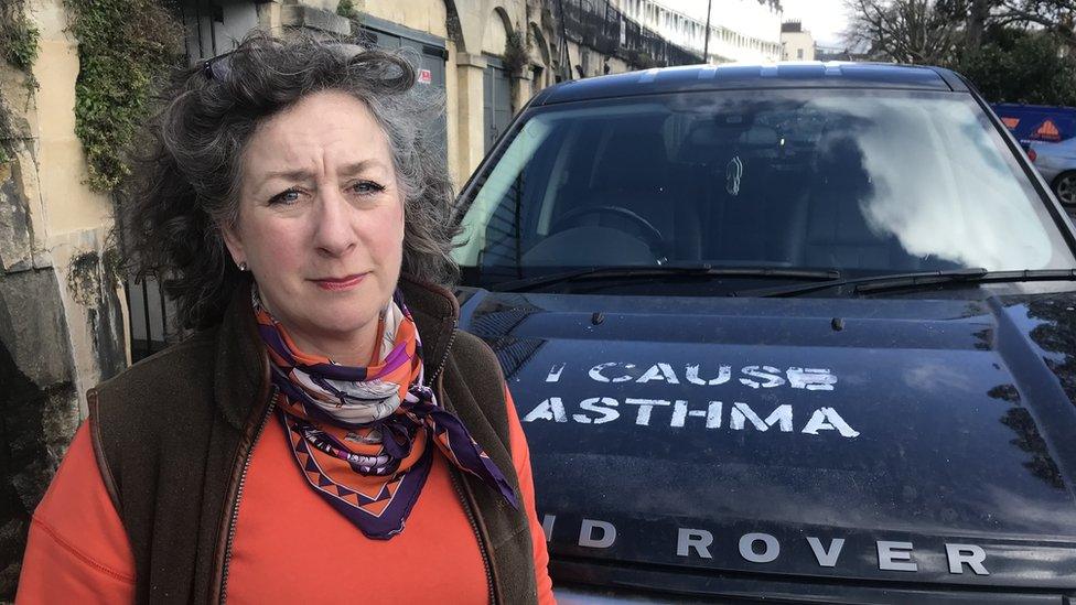 A woman standing in front of a Land Rover which has been vandalised