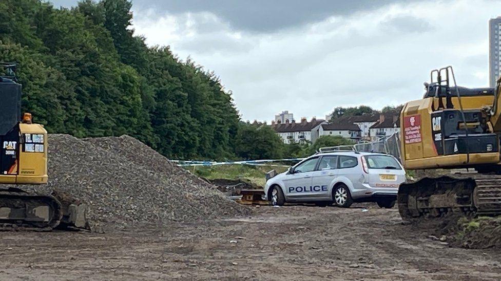 police car and diggers at a building site with a pile of rubble